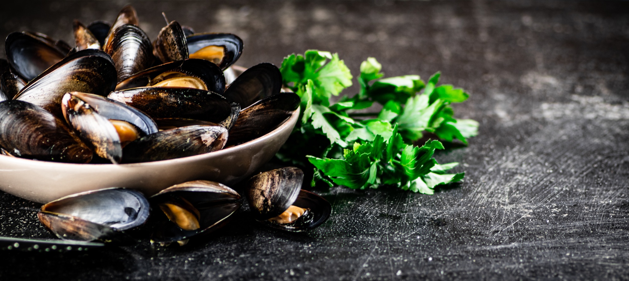 Boiled mussels in a bowl with parsley.