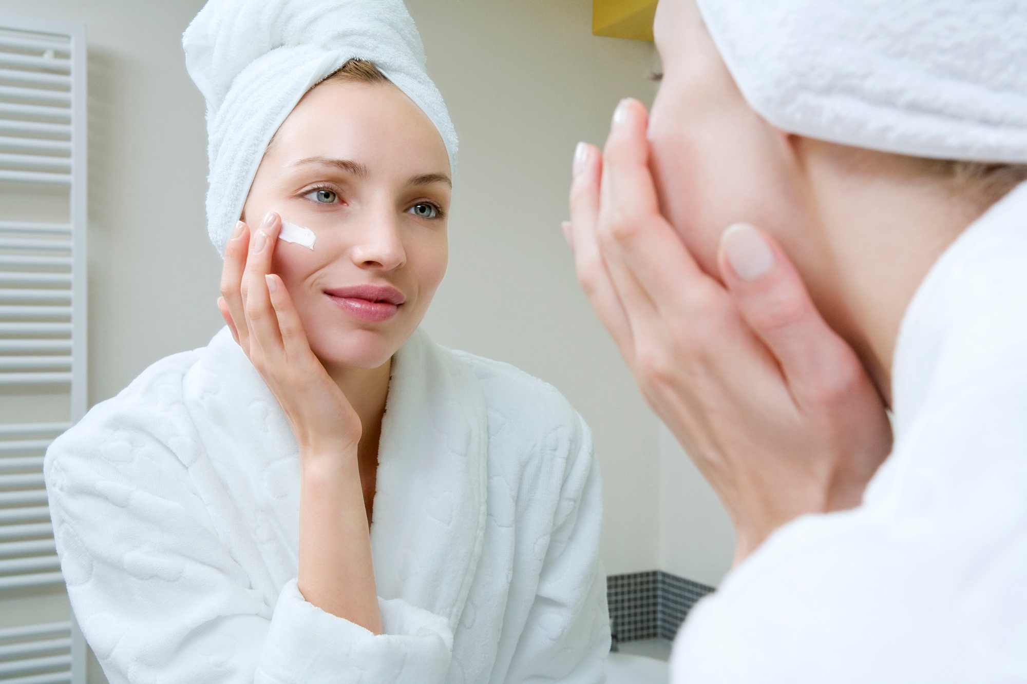 Young woman applying beauty cream