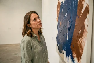 Femme contemplant une toile abstraite aux couleurs vives dans une galerie d'art contemporaine